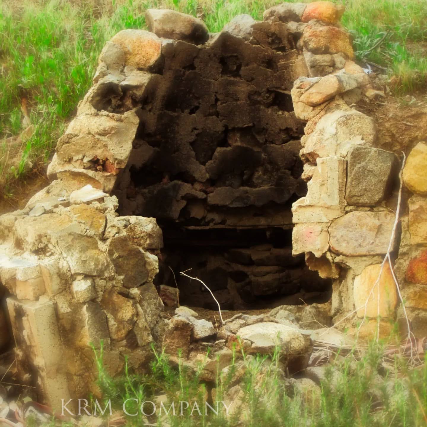 Crumbling stone fireplace overtaken by spring grass
