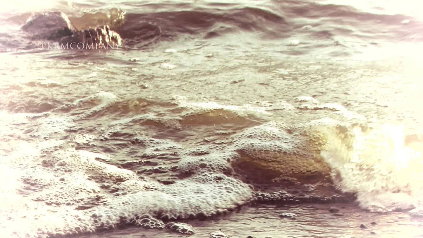 Sea foam washing over wet sand in soft washed-out light
