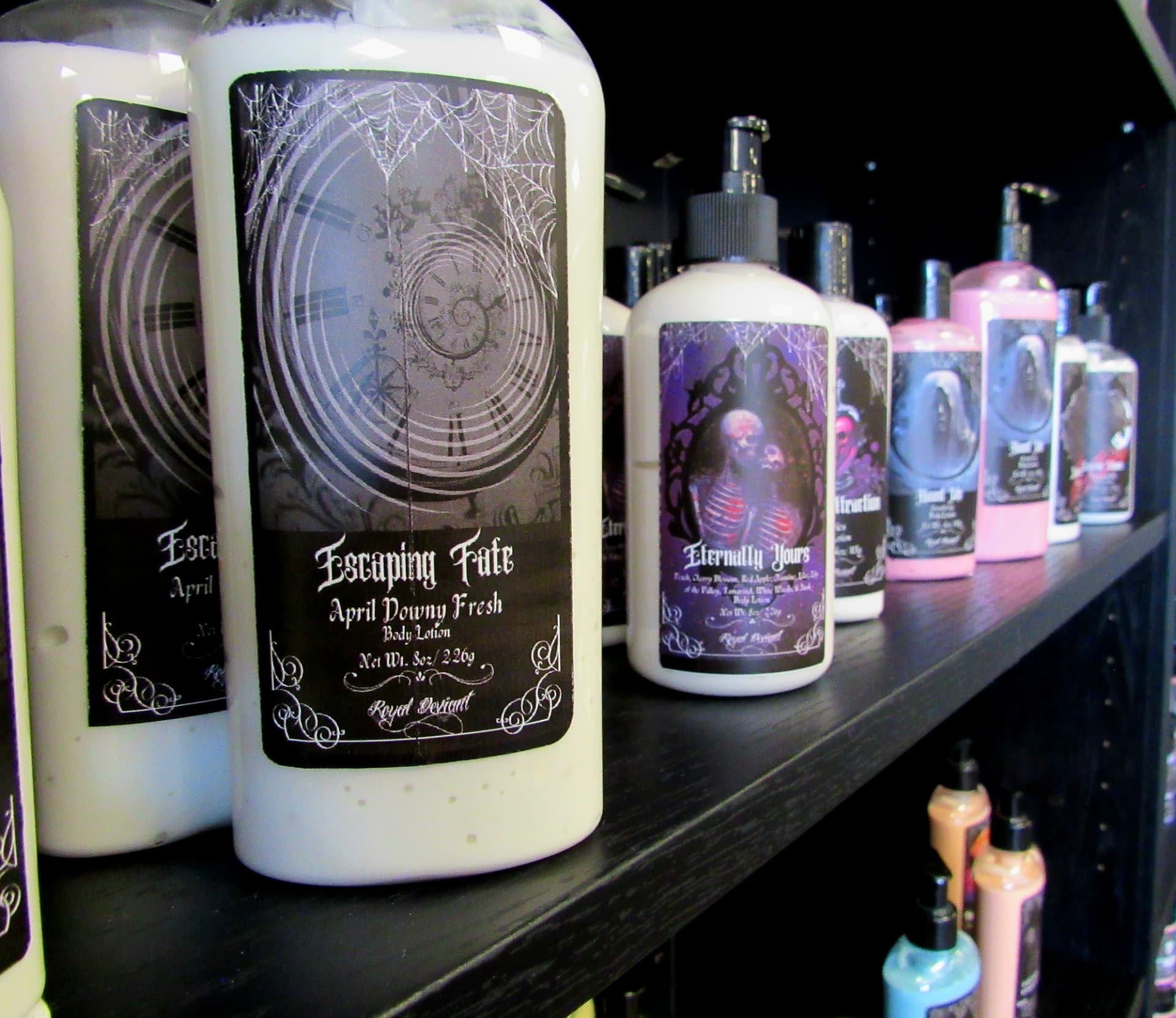 Row of illustrated body lotion bottles lined along a dark retail shelf